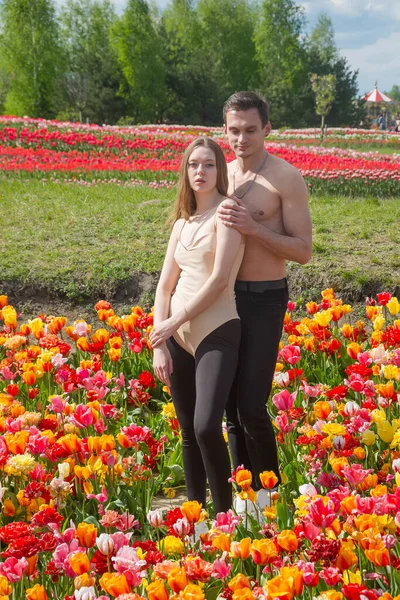 Młoda Piękna Uśmiechnięta Para Siedzi Tle Pola Kolorowych Tulipanów Guy — Zdjęcie stockowe
