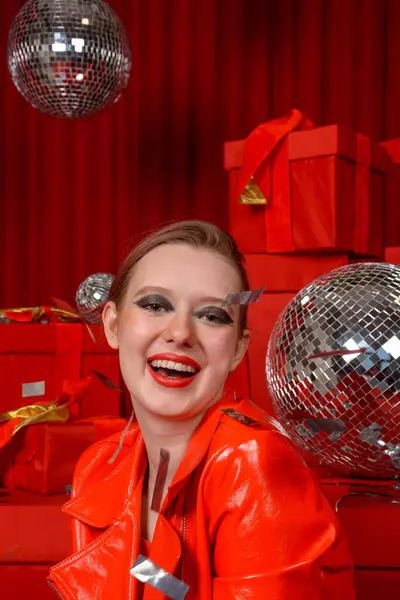 Beautiful girl in shiny red patent leather jacket at a  red festive location. Photo shoot in the studio, celebration