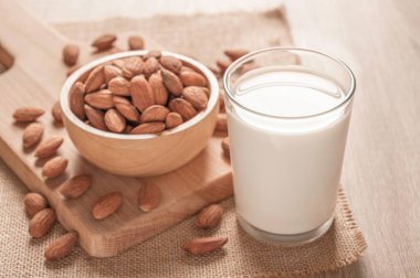 Tahta masada bir şişe badem sütü ve badem.