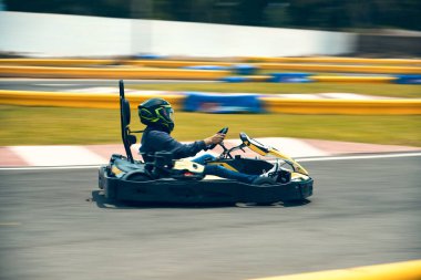 Vitesli ve kasklı bir sürücü yarış arabası sürer. İş üstündeyken. Go kart yarışları, sreet karting, kira. Ekstrem. Sürücüler için eğlenceli bir eğlence. Yumuşak ışık parıltısı, boşluğu kopyala
