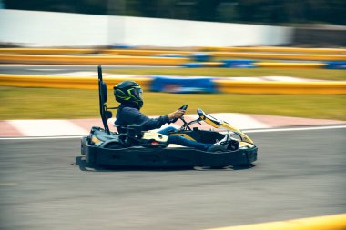 A driver in gear and helmet drives a racing car. In action. Go karts racing, sreet karting, rent. extreme sport. fun entertainment for drivers. Soft light glow, copy space clipart