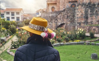 Cusco, Peru 'daki Qorikancha iç bahçelerini keşfeden şık bir turist. Tarihle doğanın büyüleyici bir karışımı..