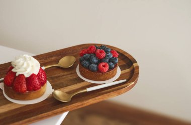 Pasta kafesinde ahududu ve kahve fincanı olan bu lezzetli çöreğin tadını çıkarın. Meyveli taze kek ve ahşap masada espresso.