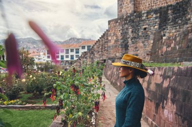 Cusco, Peru 'daki Qorikancha iç bahçelerini keşfeden şık bir turist. Tarihle doğanın büyüleyici bir karışımı..