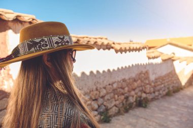 Stone 'da oturan güneş şapkalı genç bir turist Chinchero, Cuzco' daki Inca kasabasının tepesine çıkıyor..