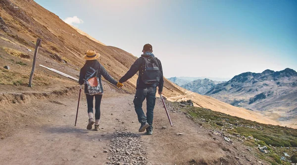 Hiking adventure healthy outdoors people standing talking. Couple enjoying view above clouds on trek. young woman and man in nature wearing hiking backpacks and sticks.