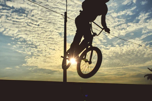 BMX bike high up in the air. Young man doing ramp jump stunt on bmx bicycle on sunset