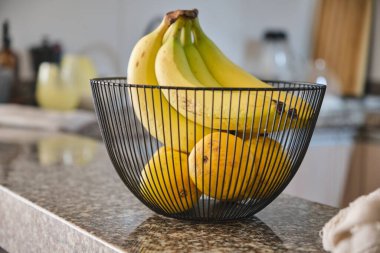 Siyah, modern meyve kasesinde muzlar. Mutfaktaki masada lezzetli meyvelerle dolu sepet, dekoratif mutfak iç dekorasyonu..