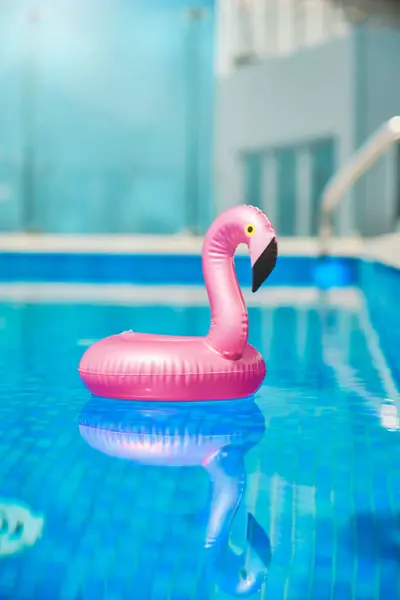 Inflatable toy of pink flamingo near swimming pool at poolside, nobody
