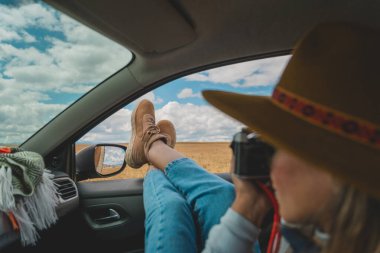 Kahverengi şapkalı bir kadın arabada yatarken kendi fotoğrafını çekiyor. Rahatlama ve rahatlama kavramı, kadın arabada eğlenirken ve gününün bir anını yakalarken.