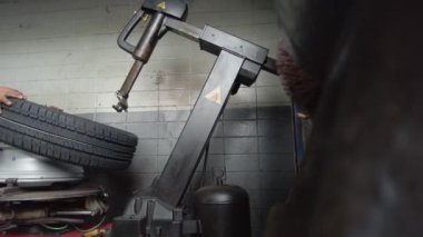 Tamirci bir makineyle lastiği kenardan çıkarıyor.