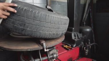 Tamirci lastik sökme makineleriyle yeni lastik değiştiriyor. Araç tamirhanesindeki atölyedeki tekerlek diskinin lastik onarımı.