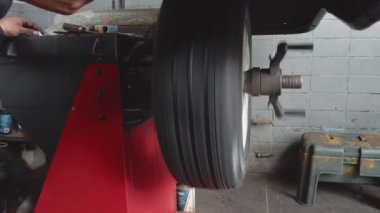 Lastik servisinde araba tekerleği dengeleniyor. Tamirci dengeleyicide otomobil tekerleği dengeliyor..