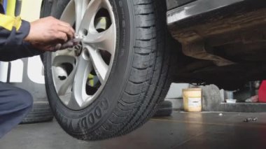 Adam, ingiliz anahtarı kullanarak kar lastiklerine geçtikten sonra tekerlek montajı yapıyor.