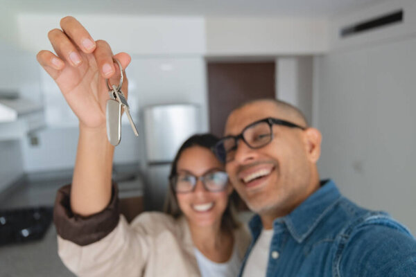 Мужчина и женщина держат ключ в руках, улыбаются и смотрят в камеру. Концепция счастья и достижения, так как пара, вероятно, празднует новый дом или новое начало
