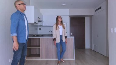 Genç bir çift yeni bir evi ziyaret ediyor, genç bir kadın erkek arkadaşıyla yeni evine taşınırken heyecanla kollarını açıyor.