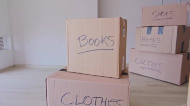 Üzerinde kitap ve giysi yazan bir yığın kutu. Kutular üst üste yığılmış ve etiketler taşınmak için paketlendiklerini gösteriyor.
