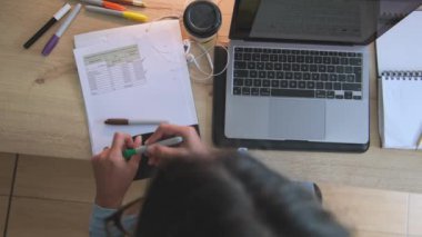 Bir kadın dizüstü bilgisayarda masada bir fincan kahveyle yazı yazıyor. Olay yeri yoğun bir iş günü olduğunu gösteriyor. Kadın muhtemelen bir proje üzerinde çalışıyor ya da rapor veriyor.