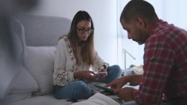 Bir adam ve bir kadın önlerinde bir yığın kıyafetle bir yatakta oturuyorlar. Kadın bir kağıt parçasına bakıyor, muhtemelen bir harita ya da bir mektup.