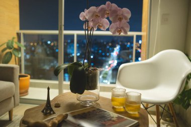 Üzerinde çiçek vazosu ve bir kitap olan bir masa. Çiçekler pembe ve kitabın adı da Eyfel Kulesi.