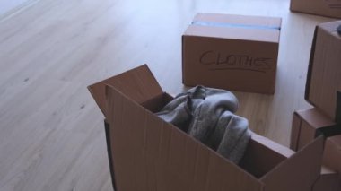 Üzerinde kitap ve giysi yazan bir yığın kutu. Kutular üst üste yığılmış ve etiketler taşınmak için paketlendiklerini gösteriyor.