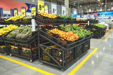 Granadilla ve avokado gibi tropikal meyveler taze ürünlerle dolu bir süpermarkette sergileniyor..