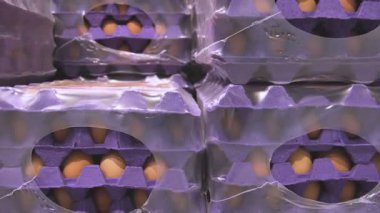 Plastik filme sarılı büyük yumurta kutuları bir depodaki paletlere yerleştiriliyor ve verimli depolama ve dağıtım hazırlıklarını gösteriyor.