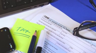 Vergi formu 1040, W-9, kalem, keçeli kalem, okuma gözlüğü ve dizüstü bilgisayar muhasebecilerin masasında.