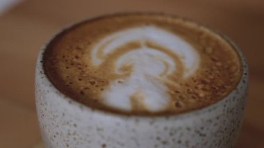 Kremalı latte sanatı nefis bir kahve içeceği üzerine oturur.