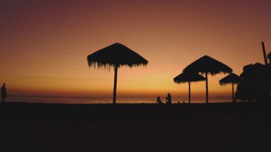 Gün batımında sahilde bisiklet süren bir sokak satıcısı silueti.