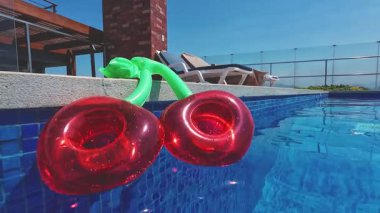 Çatısı olan lüks bir yüzme havuzunda yüzen şişme kirazlar.