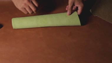 Sanatçı kağıt şablonu kullanarak deriye yapıştırıcı sürüyor.