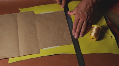 Zanaatkar titizlikle çelik cetvel ve özel aletler kullanarak deriyi keser, el yapımı deri işçiliğinin hassasiyetini ve sanatını vurgular.