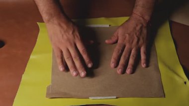 Sanatçı kağıt şablonu kullanarak deriye yapıştırıcı sürüyor.