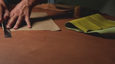 Bir tezgahta deri işi yapan, yuvarlanan ve yumuşayan bir zanaatkar.