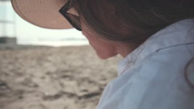 Yaz tatili boyunca sahilde kitap okuyan genç bir kadına yakın.