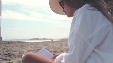 Turist, yaz tatilinde kumsalda dinlenirken kitap okumaktan zevk alıyor.