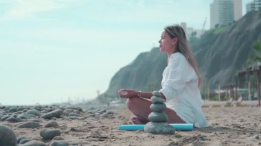 Yoga hocası sakin bir plajda çeşitli asana egzersizleri yapıyor.