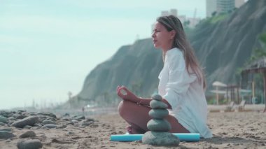 Güneşli bir plajda huzurlu bir yoga pratiği fiziksel ve zihinsel sağlığı arttırır.
