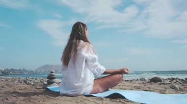Yoga hocası sakin bir plajda çeşitli asana egzersizleri yapıyor.