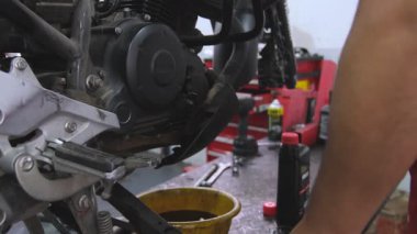 Bir tamircide motosiklet motorundan cıvata çıkaran bir motosiklet tamircisi.