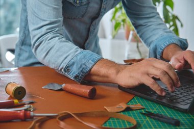 Deri ustası atölyedeki küçük işletmeleri dizüstü bilgisayarla yönetiyor.