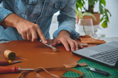 Zanaatkar atölyesinde deri elleme, küçük işletme ve girişimcilik kavramını kullanıyor.