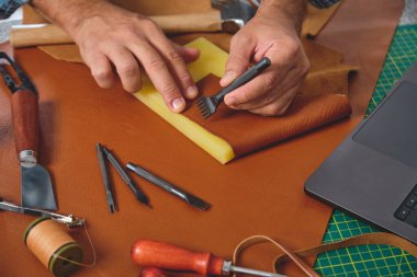 Zanaatkar atölyesinde deri elleyerek dikiş atıyor.