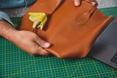 Zanaatkar el yapımı deri çanta sunar, küçük işletme zanaatı ve detaylara dikkat gösterilir.