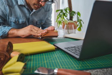 Bir atölyede deriyle çalışan bir zanaatkar, el yapımı ürünler üretiyor.