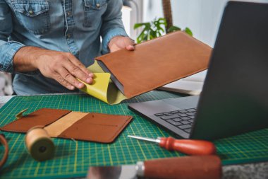 Deri atölyesinde çalışan bir zanaatkar yeni ürünler üretmek için malzeme hazırlıyor.