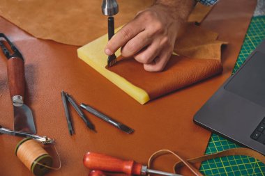 Geleneksel bir atölyede çekiç ve yumruk aleti kullanan bir zanaatkar, el yapımı ürünler yaratıyor.