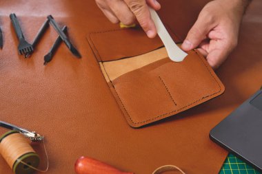 Deri işçisi atölyesinde çalışıyor. Geleneksel aletlerle cüzdan yapıyor.