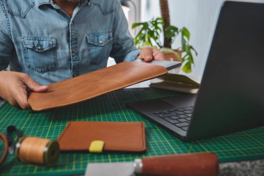 Deri ustası dizüstü bilgisayarı özel yapım deri bir çantaya yerleştiriyor, el işi ve küçük işletme girişimciliği sergiliyor.